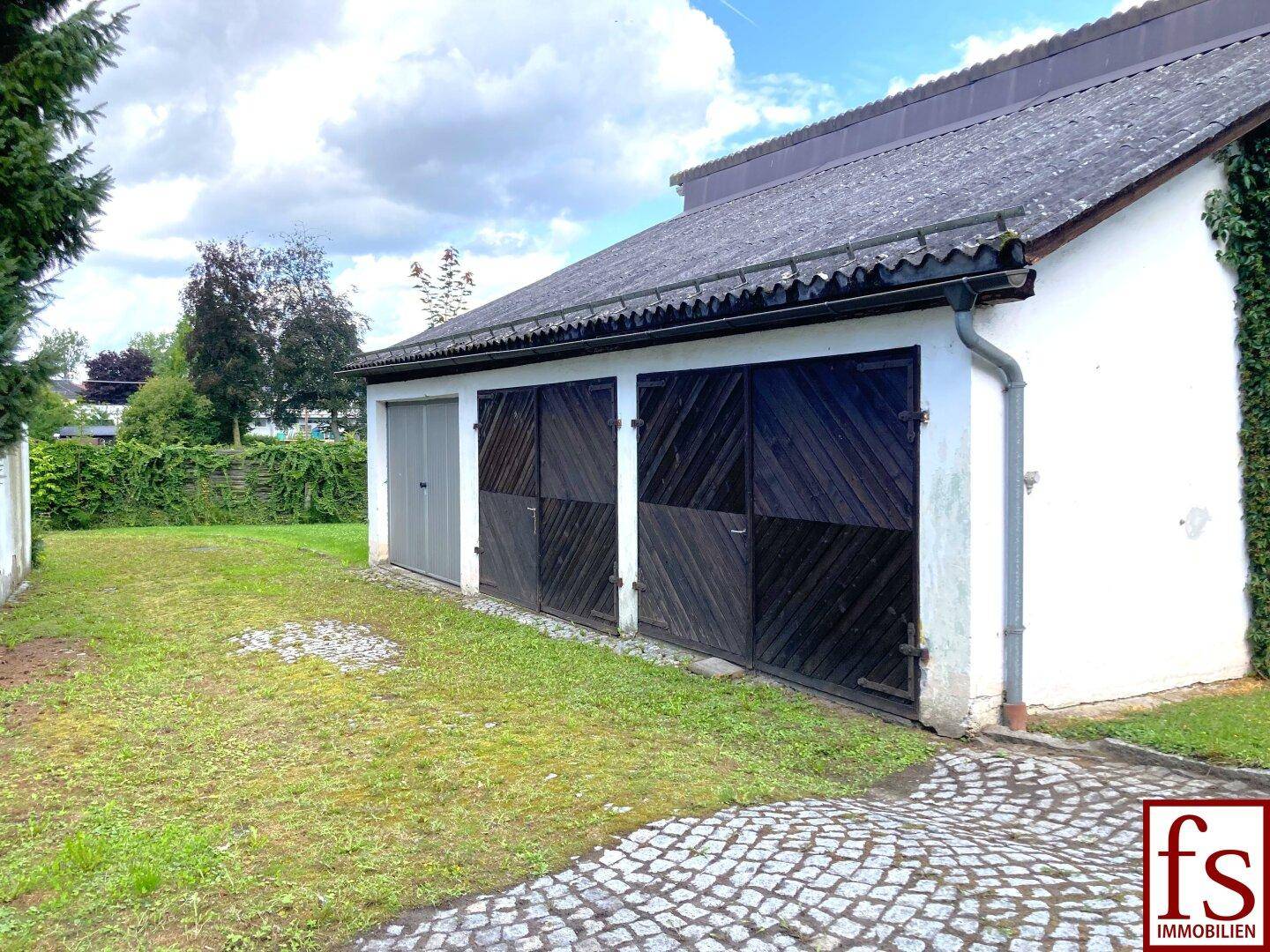 Garagengebäude mit mehreren Stellplätzen und einem Rasenbereich davor.