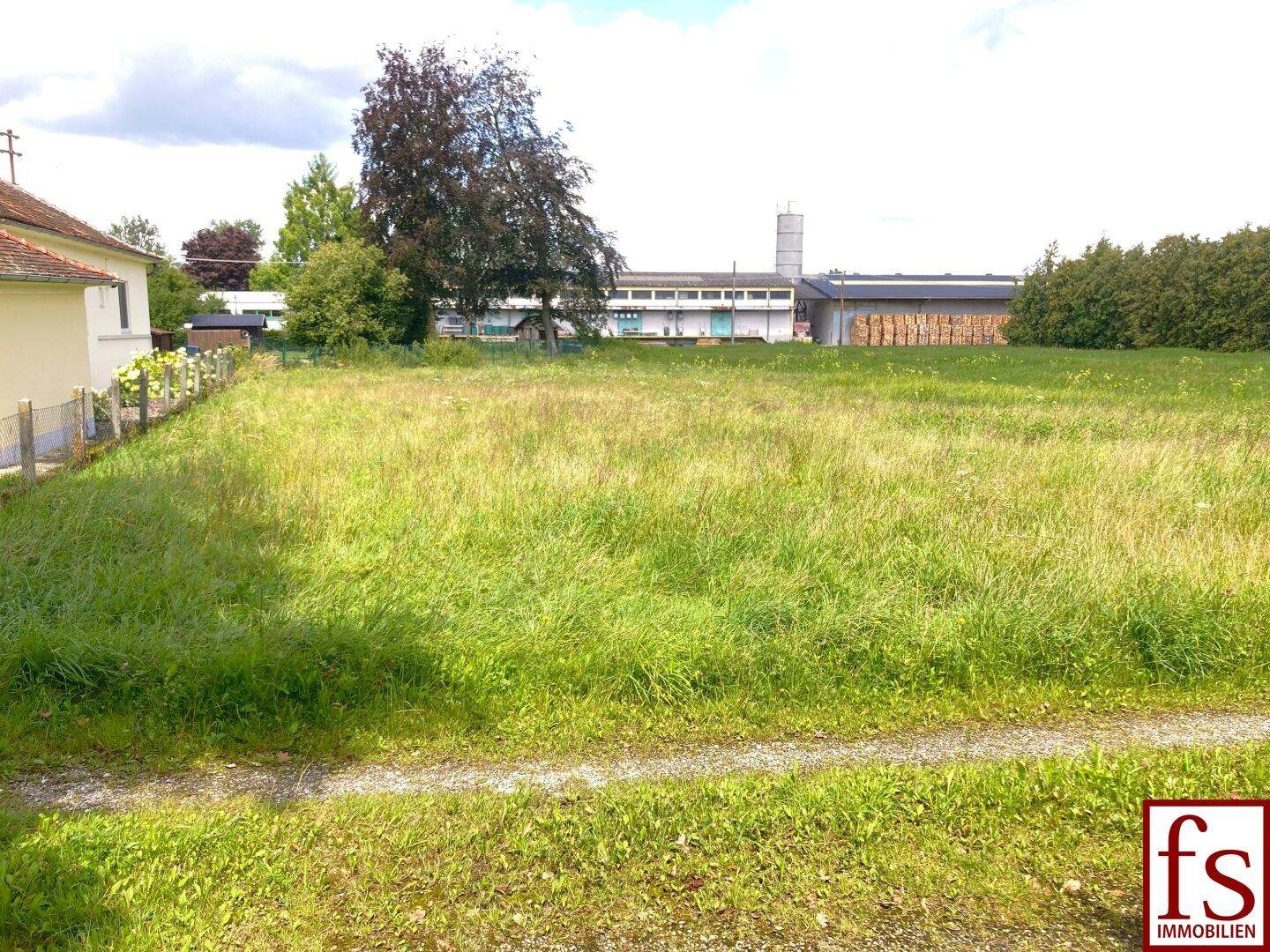 Weitläufiges, unbebautes Grundstück mit hohem Gras und Blick auf umliegende Gebäude.