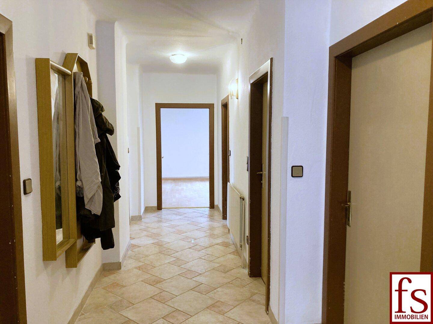 Heller Flur mit Fliesenboden und mehreren Türen, die zu den angrenzenden Räumen führen.