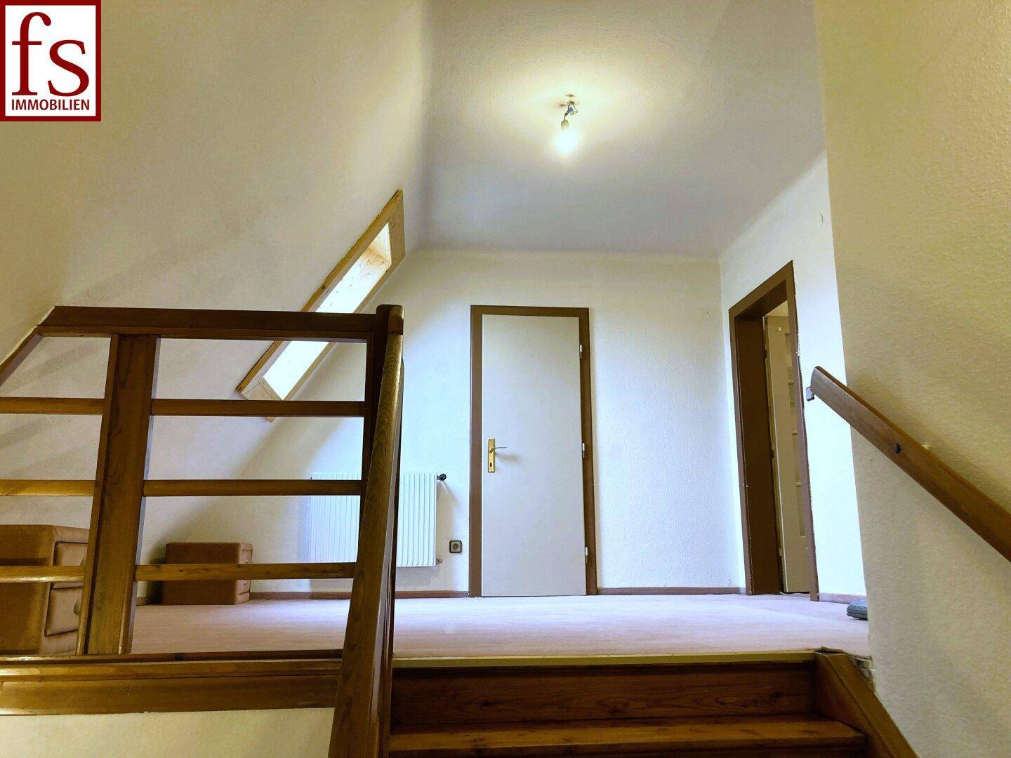 Heller Treppenabsatz im Obergeschoss mit Holzboden und Zugang zu weiteren Räumen.