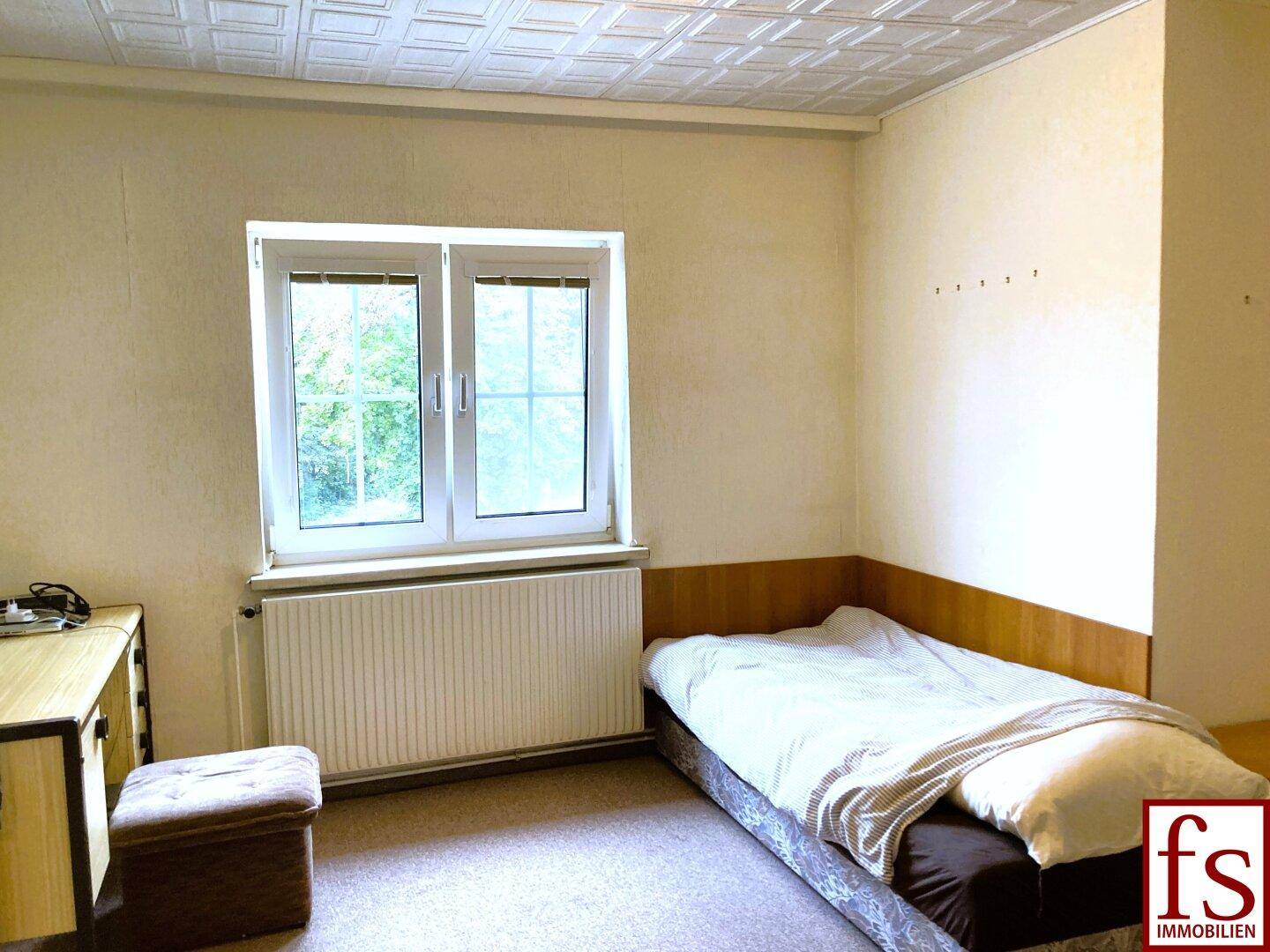 Helles Schlafzimmer mit Einzelbett, Teppichboden und Fenster, das den Raum erhellt.