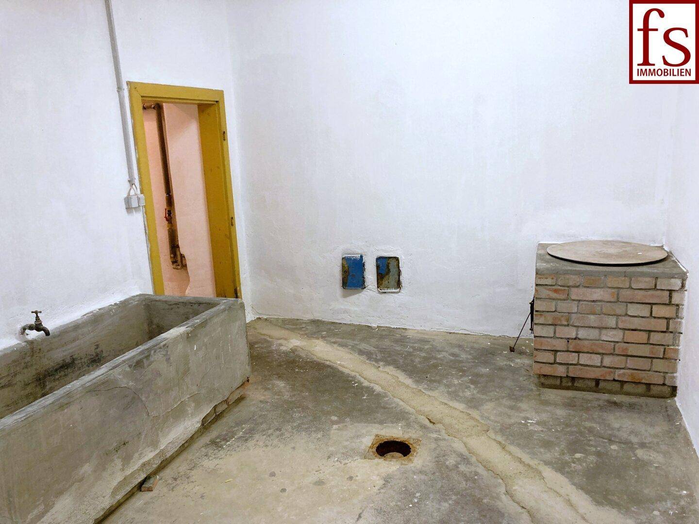 Kellerraum mit Waschbecken, gemauertem Podest und Betonboden, ideal für Hauswirtschaft.