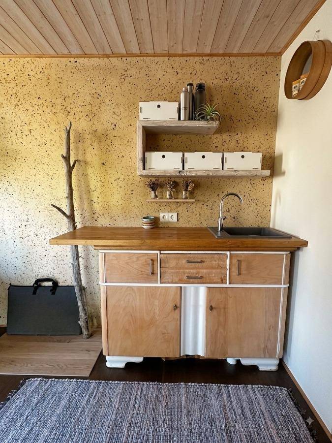 Kleine Küchenzeile mit Holzarbeitsplatte, Spüle und rustikalen Holzschränken.