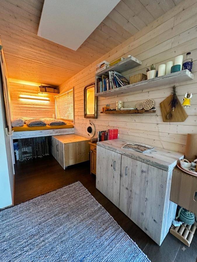 Gemütlicher Schlafbereich mit erhöhtem Bett, Holzverkleidung und integrierten Stauräumen.