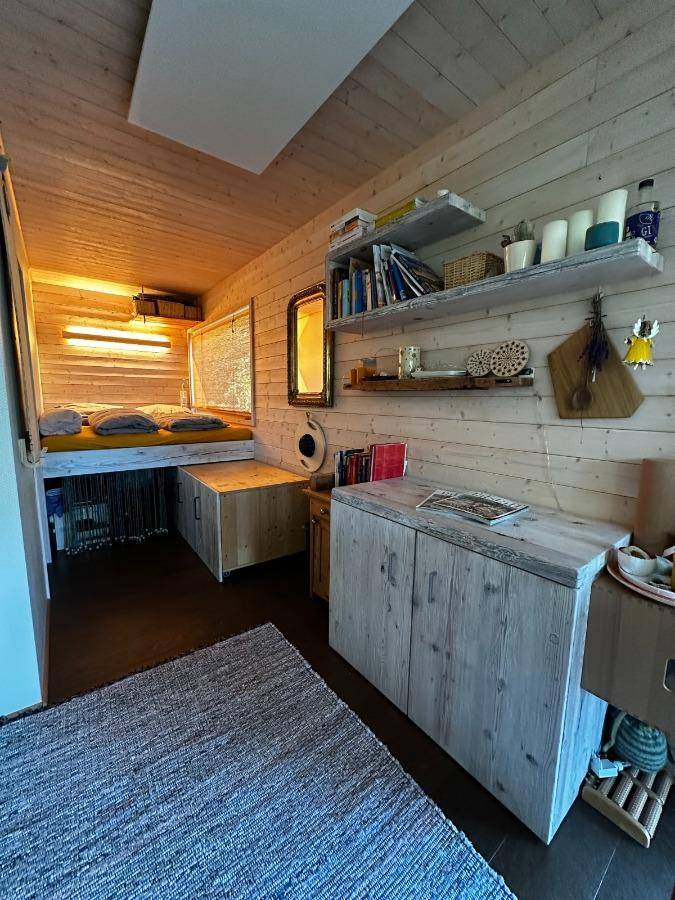 Gemütlicher Schlafbereich mit erhöhtem Bett, Holzverkleidung und integrierten Stauräumen.