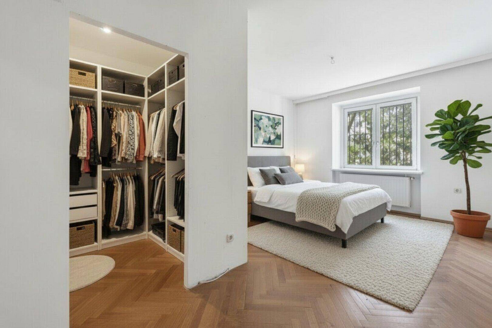 Schlafzimmer mit Doppelbett, Teppich und angrenzendem begehbarem Kleiderschrank.