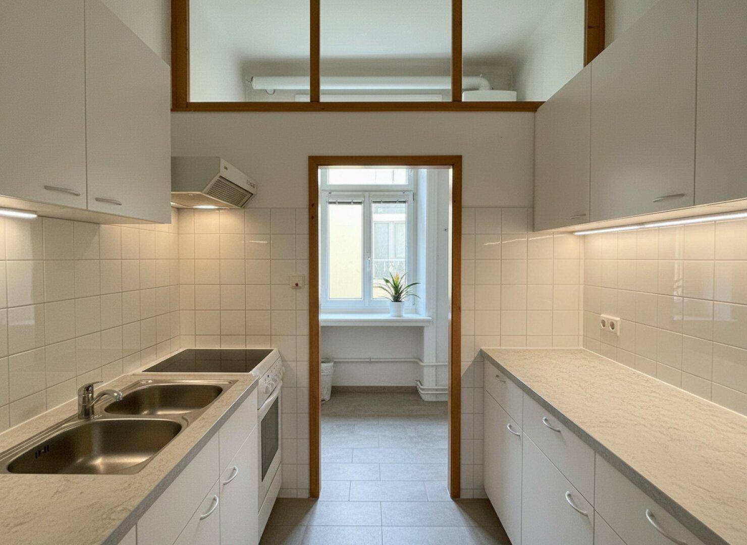 Moderne Küche mit weißen Schränken, integrierten Geräten und Fliesenboden.