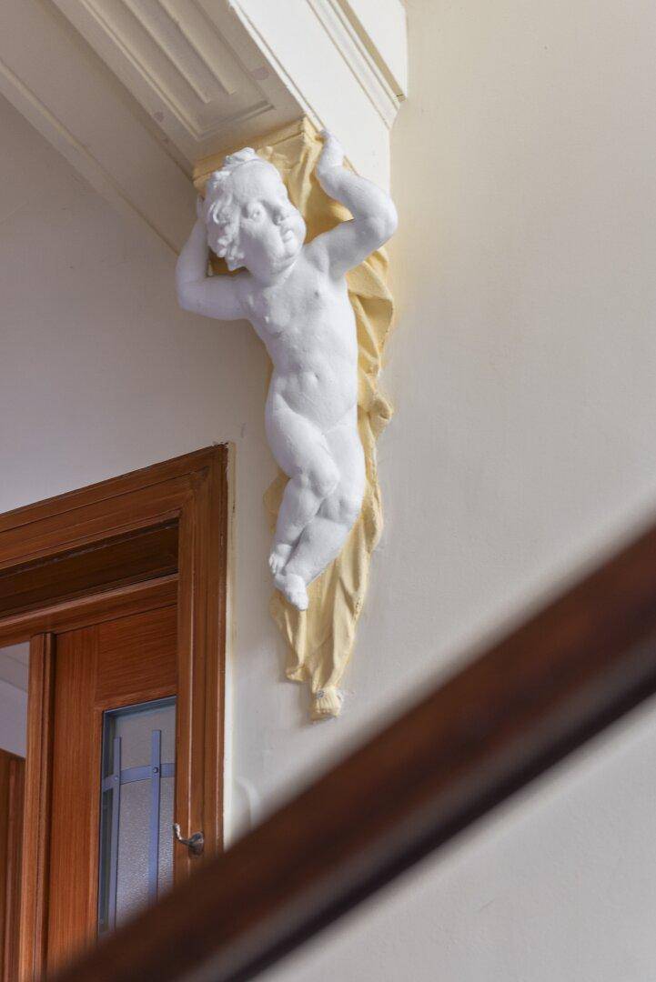 Stuckverzierung eines Putten an der Wand, ein klassisches Detail im Eingangsbereich.