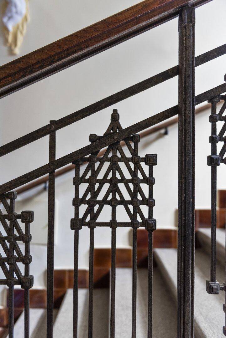 Detailansicht eines kunstvoll geschmiedeten Treppengeländers mit geometrischen Mustern.