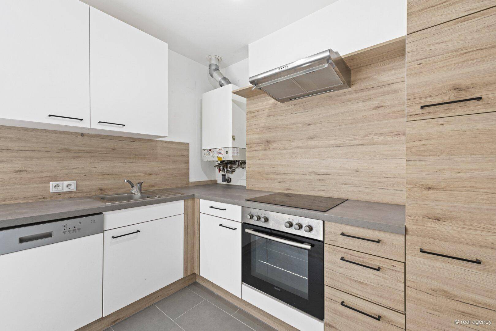 Moderne Einbauküche mit weißen und holzfarbenen Fronten, ausgestattet mit Geräten und Boiler.