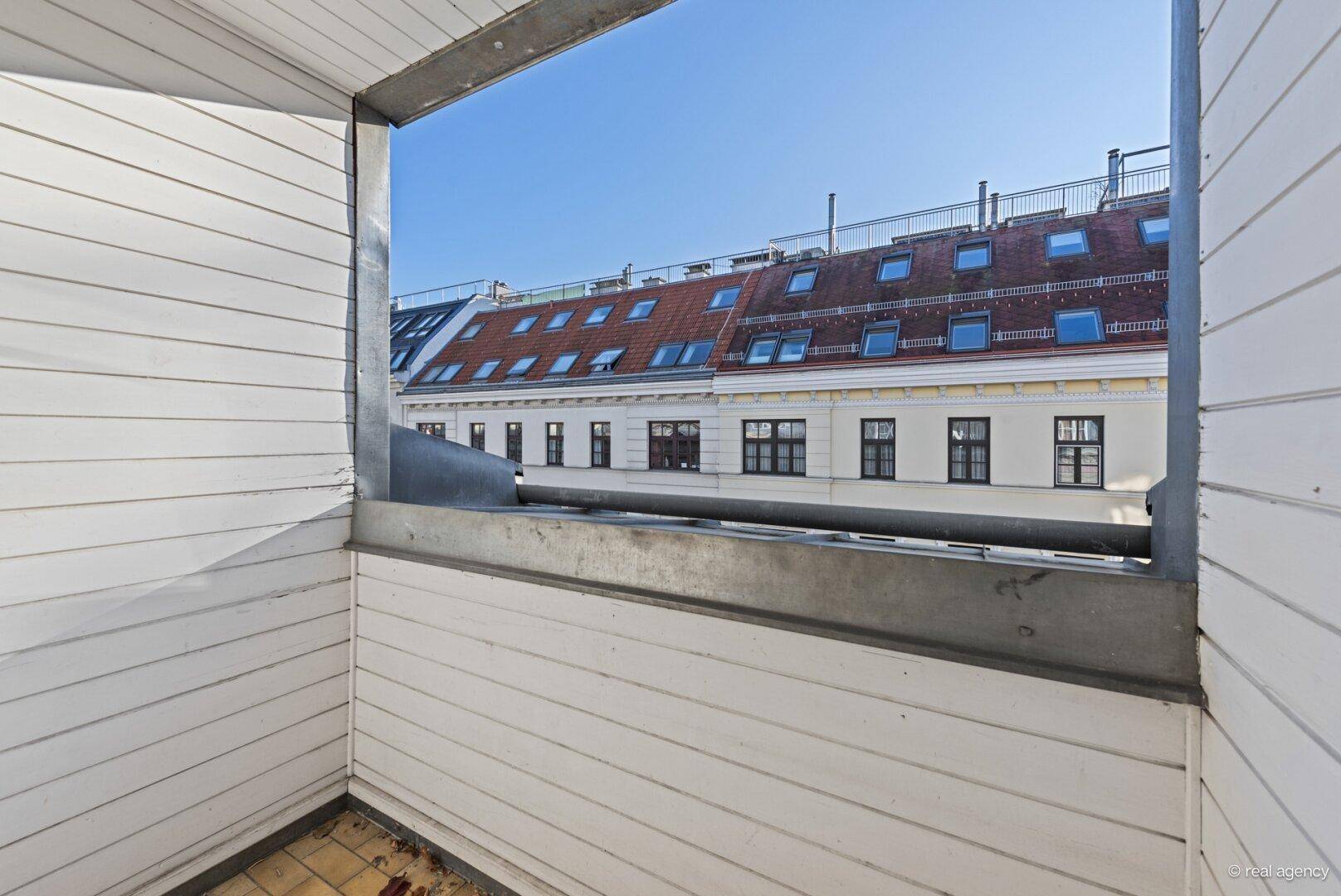 Kleiner Balkon mit Blick auf die umliegenden Gebäude und deren Mansarddächer.