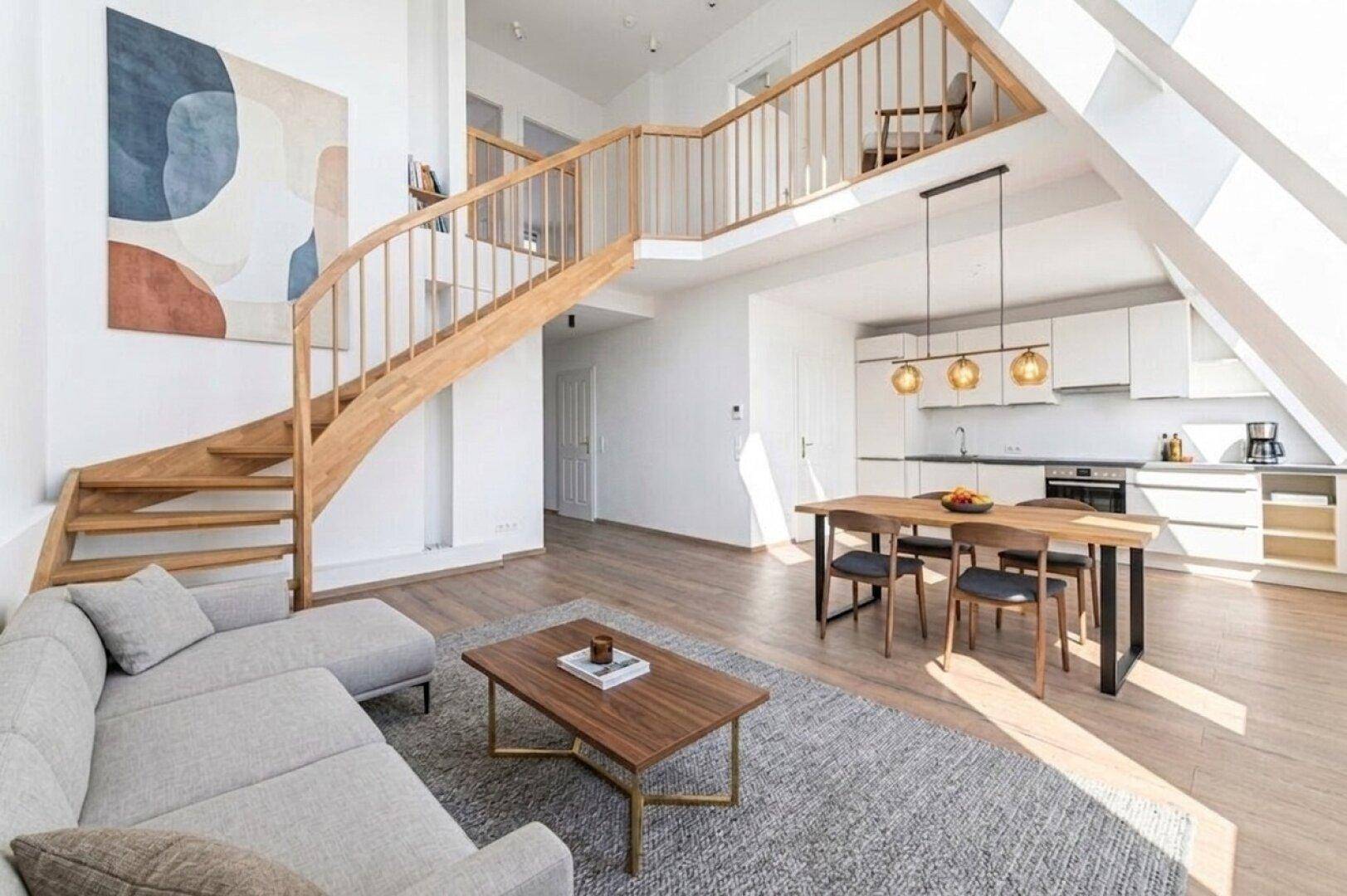 Helles, offenes Wohn-Esszimmer mit moderner Küche, Holztreppe und Dachschrägenfenstern.