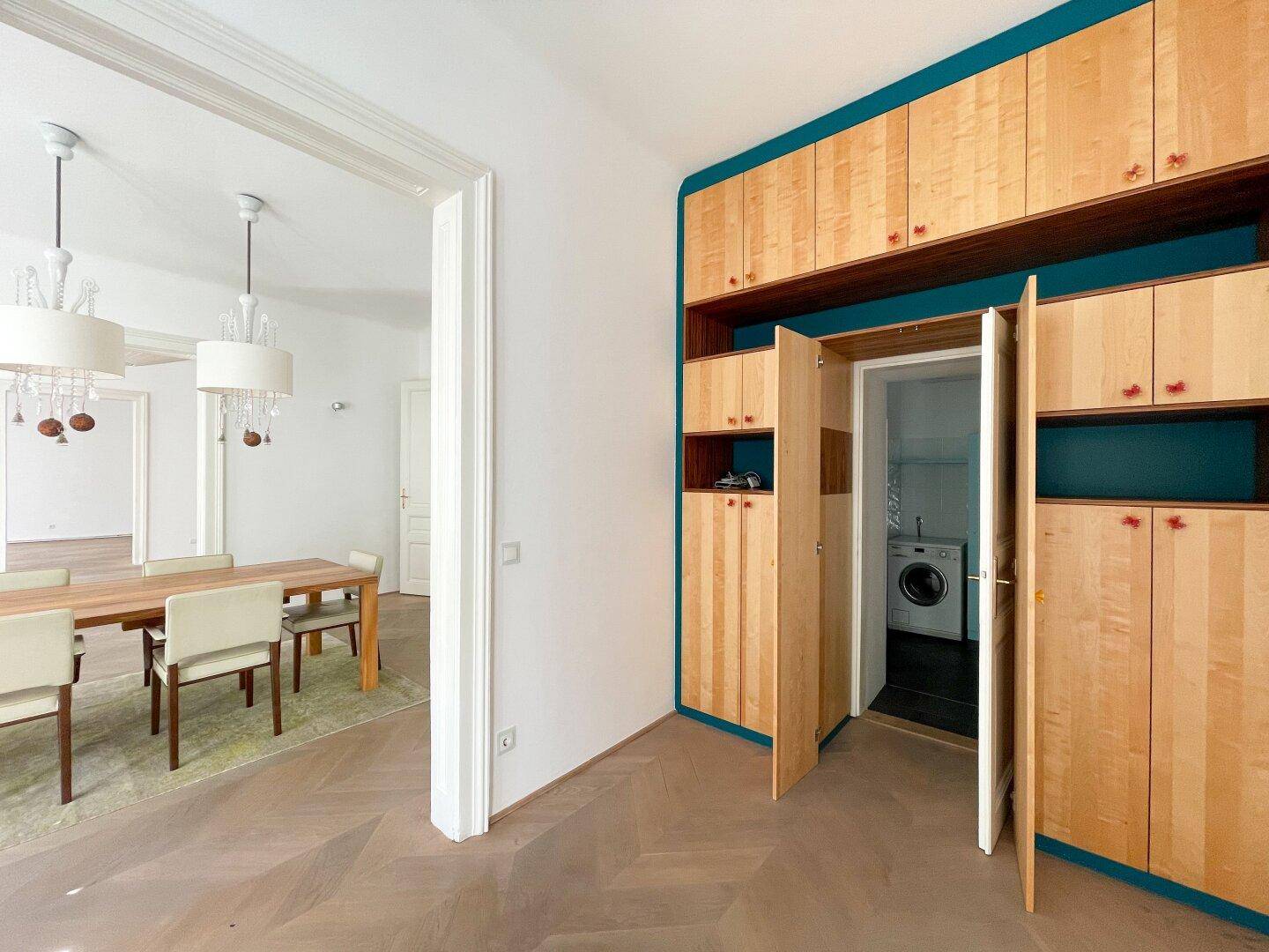 Flur mit maßgefertigten Holzschränken und Zugang zu Esszimmer und Hauswirtschaftsraum.
