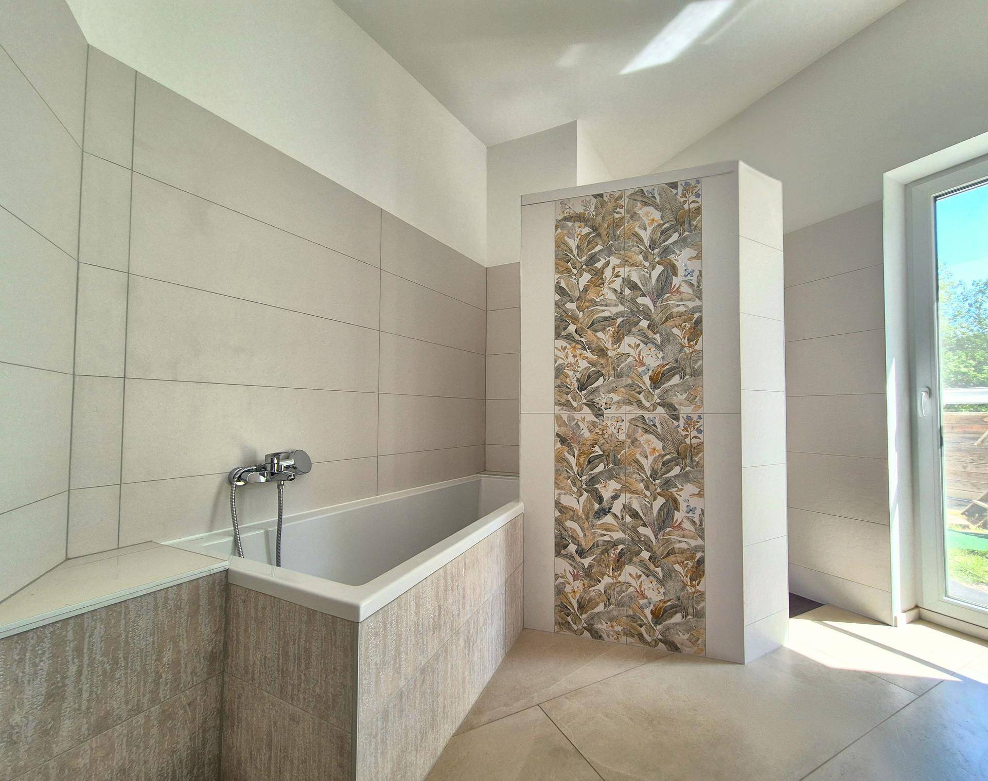 Modernes Badezimmer mit Badewanne, großen Fliesen und einem Fenster für natürliches Licht.