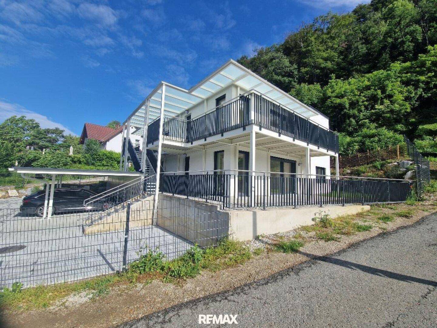 Moderner Wohnkomplex mit Carport und Balkonen, umgeben von Natur und mit guter Anbindung.