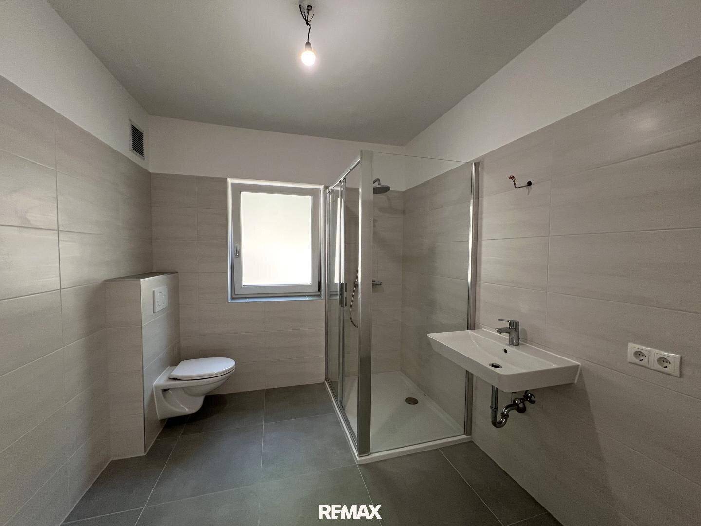 Modernes Badezimmer mit begehbarer Dusche, Wand-WC und Fenster für natürliche Belüftung.