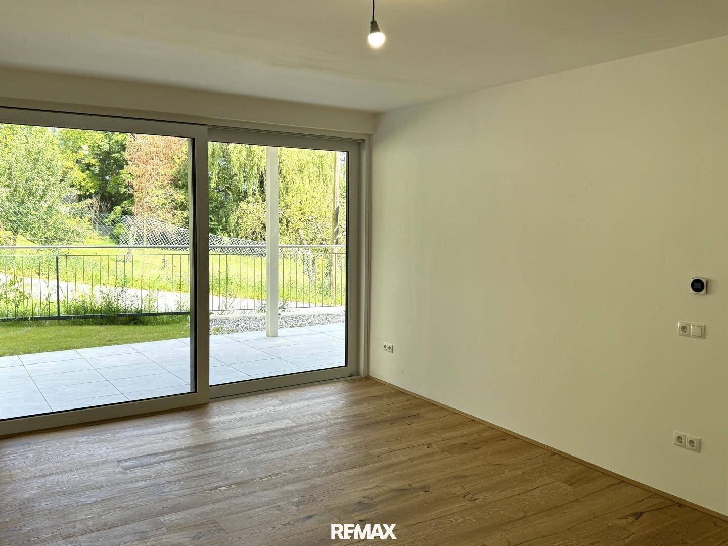 Helles Wohnzimmer mit Holzboden und großer Schiebetür, die Zugang zur Terrasse bietet.