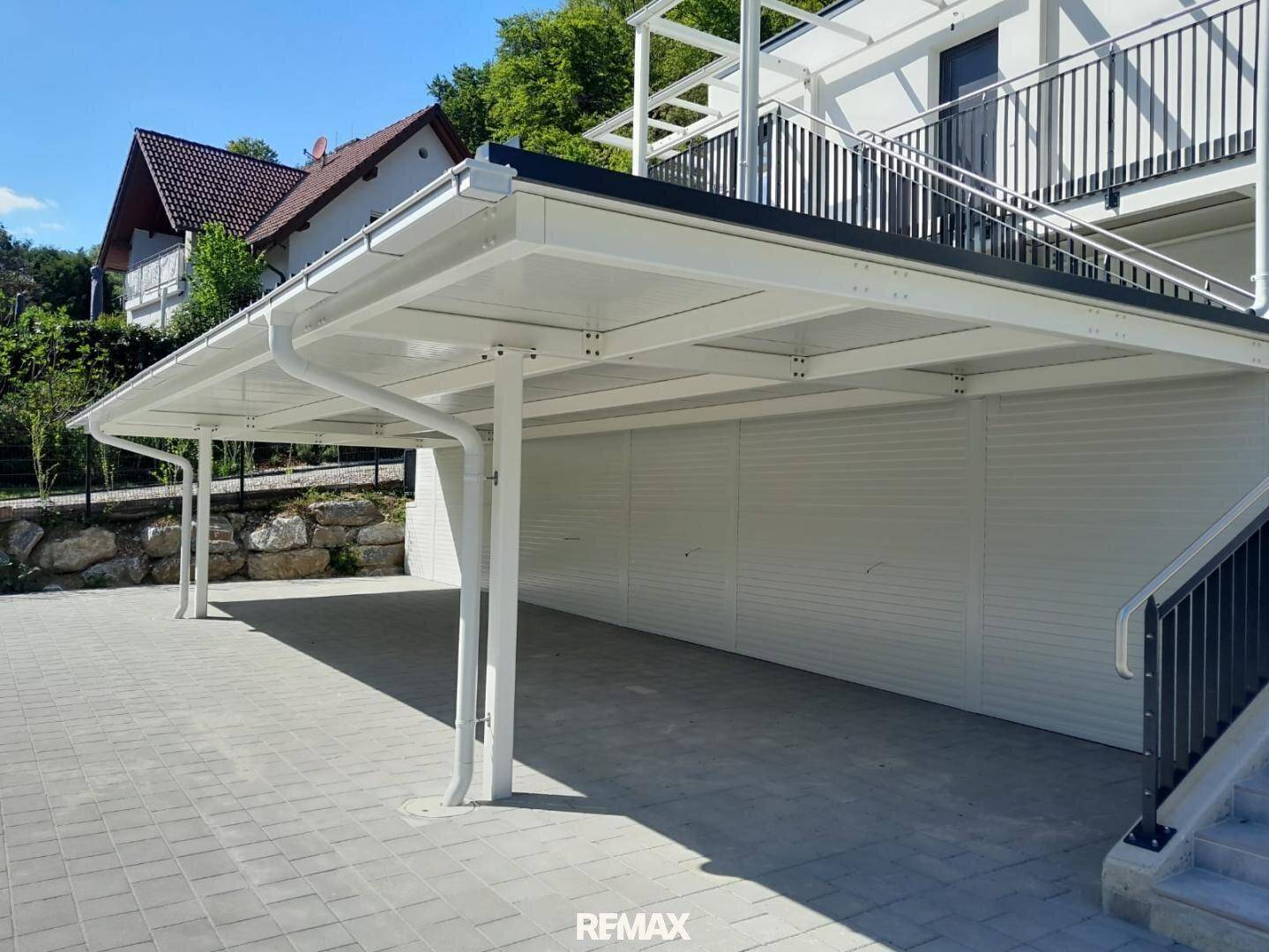 Geräumiger Carport mit gepflasterter Zufahrt, bietet geschützten Parkraum für Fahrzeuge.