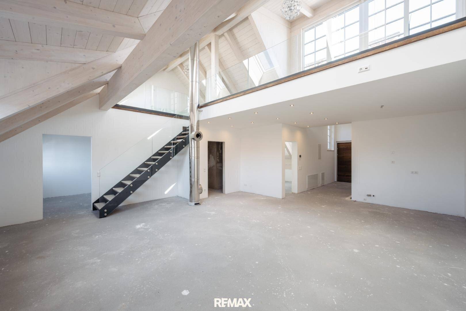 Geräumiger, offener Dachbodenbereich mit hohen Decken, sichtbaren Holzbalken und großen Fenstern.