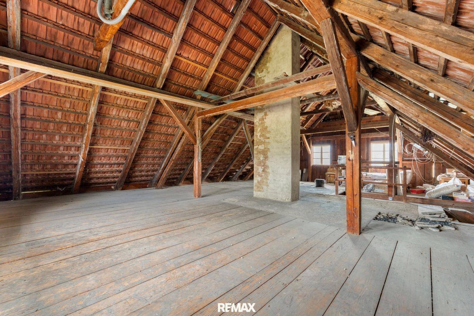Großer Dachboden mit sichtbarer Holzkonstruktion, Ziegeldach und Holzboden.