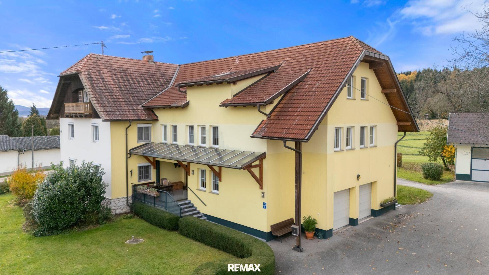 Ansicht des Haupthauses mit gelber Fassade, rotem Ziegeldach und einem gepflegten Vorgarten.