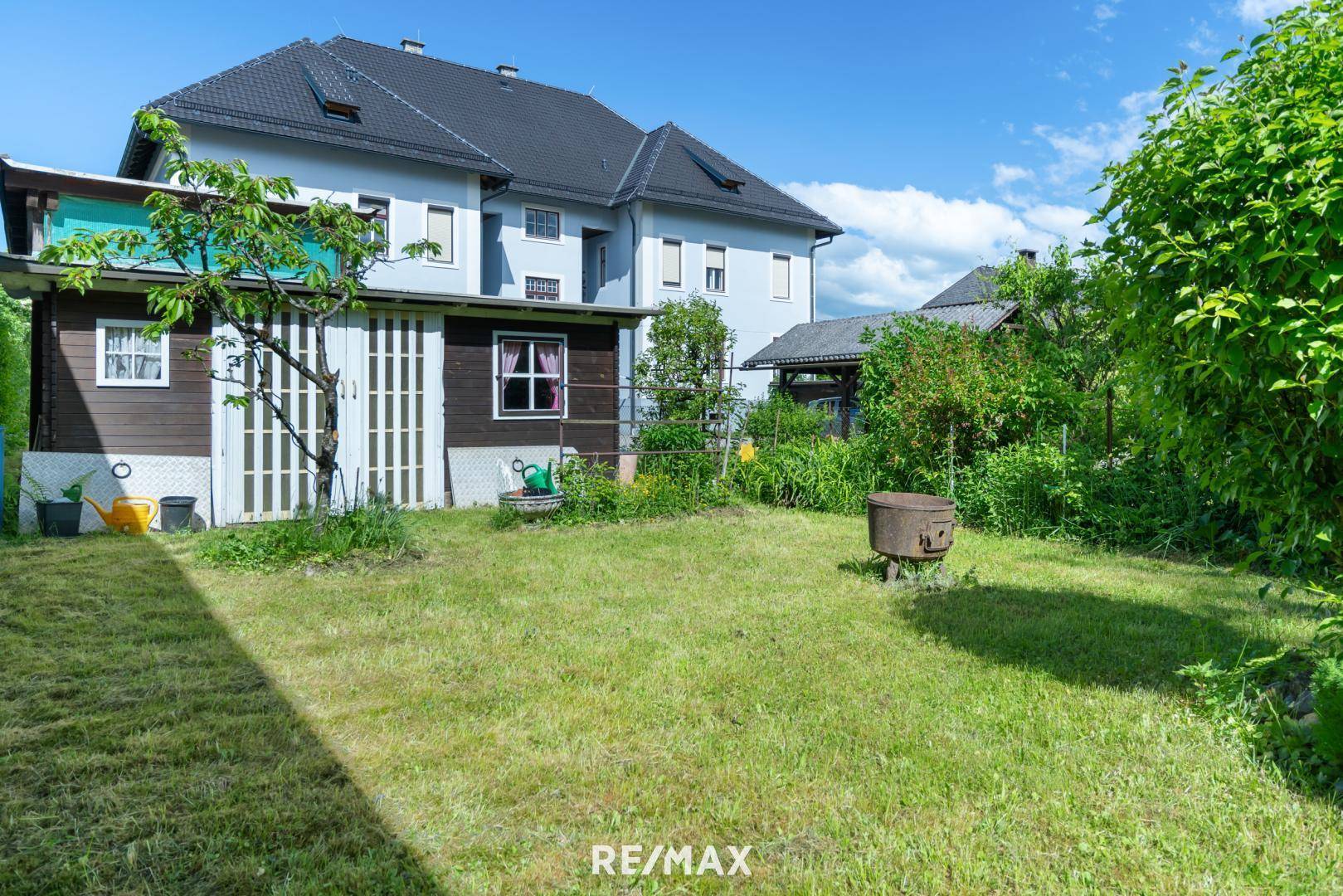 Hinterer Gartenbereich mit Rasen, Gartenhaus und Blick auf das Hauptgebäude.
