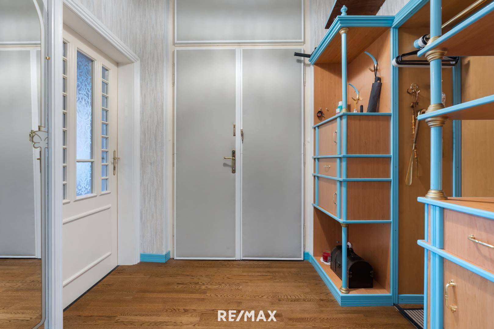 Flur mit Holzboden und offenem Regalsystem, das als Garderobe dient.