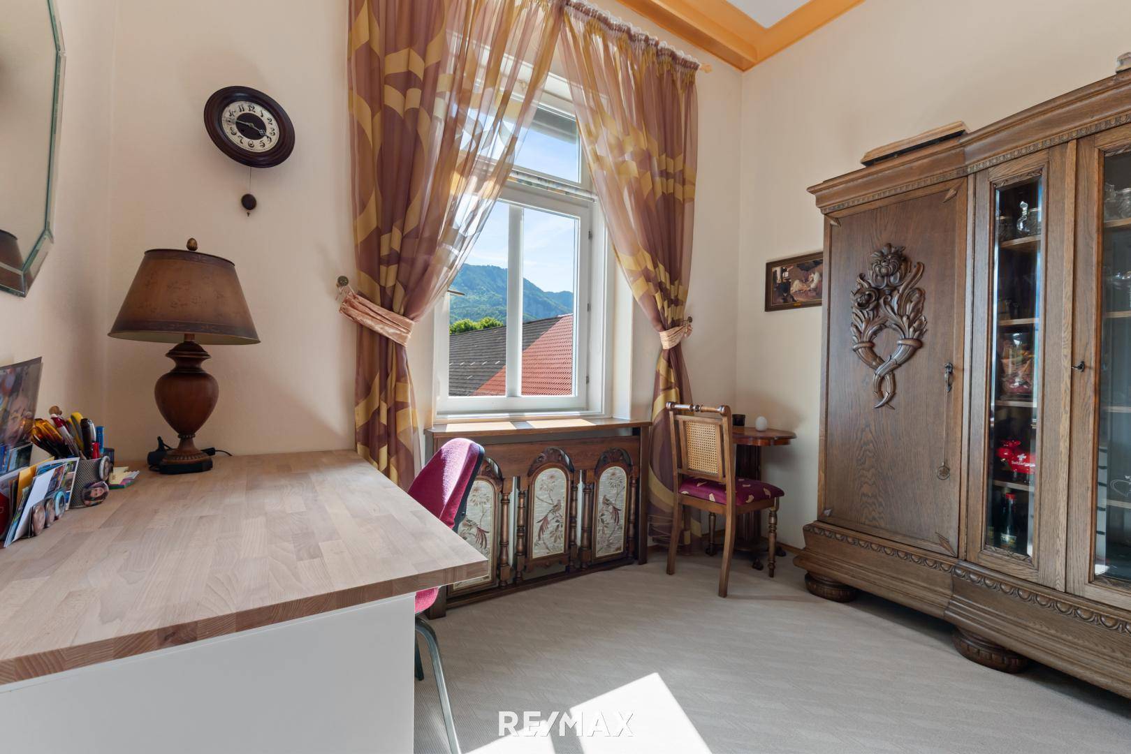 Arbeitszimmer mit Holzmöbeln, Teppichboden und Fenster mit Blick auf die umliegende Landschaft.