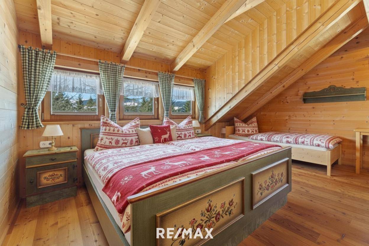 Gemütliches Schlafzimmer im Dachgeschoss mit Holzbalken, traditionellen Möbeln und Blick auf die Berge.