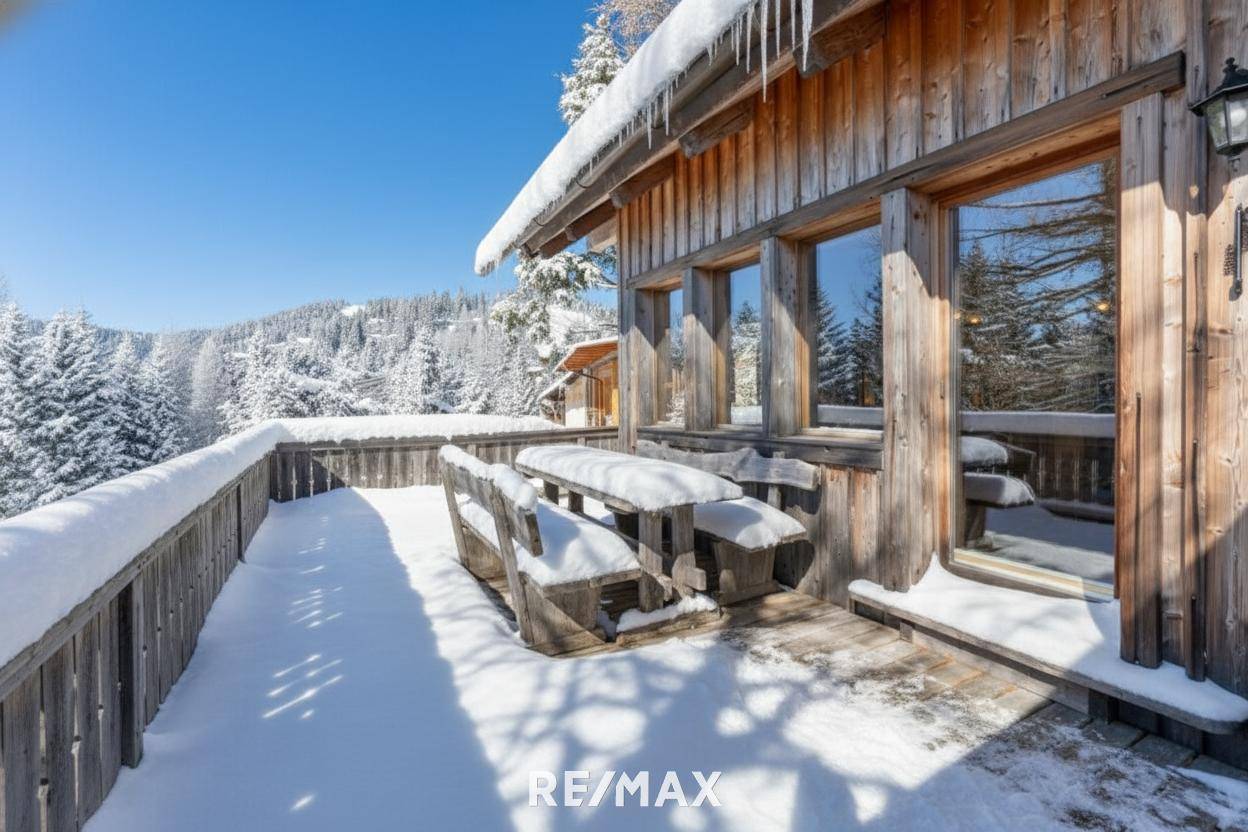 Geräumige Holzterrasse mit rustikalen Sitzgelegenheiten, bedeckt mit Schnee und einem weiten Bergblick.