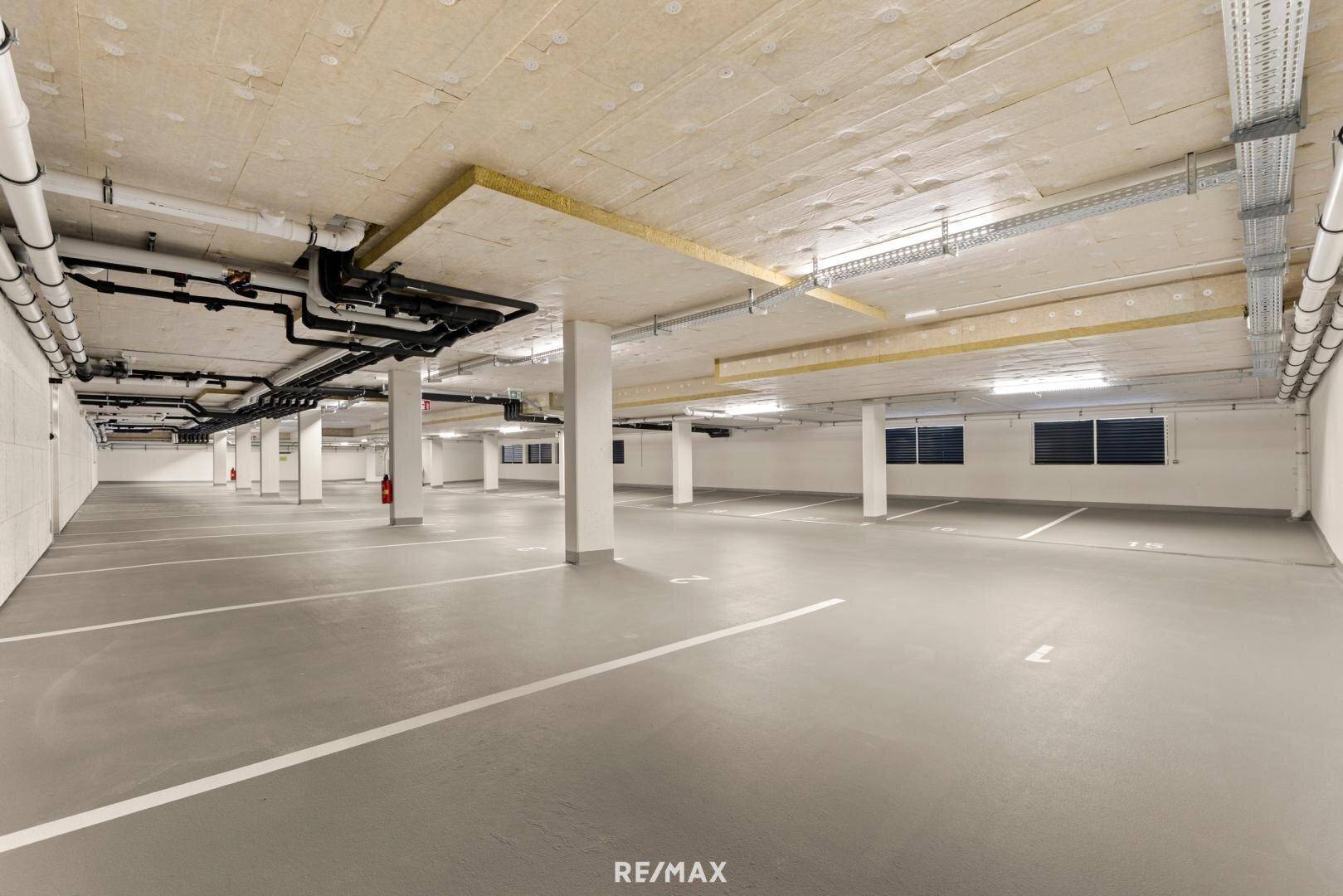 Weitläufige Tiefgarage mit zahlreichen Parkplätzen und moderner Infrastruktur.
