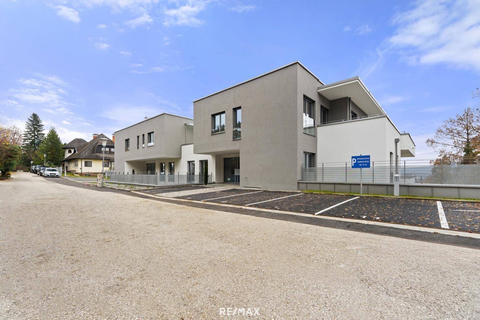 Neubau-Wohngebäude mit modernen Fassaden und Außenparkplätzen an einer ruhigen Straße.