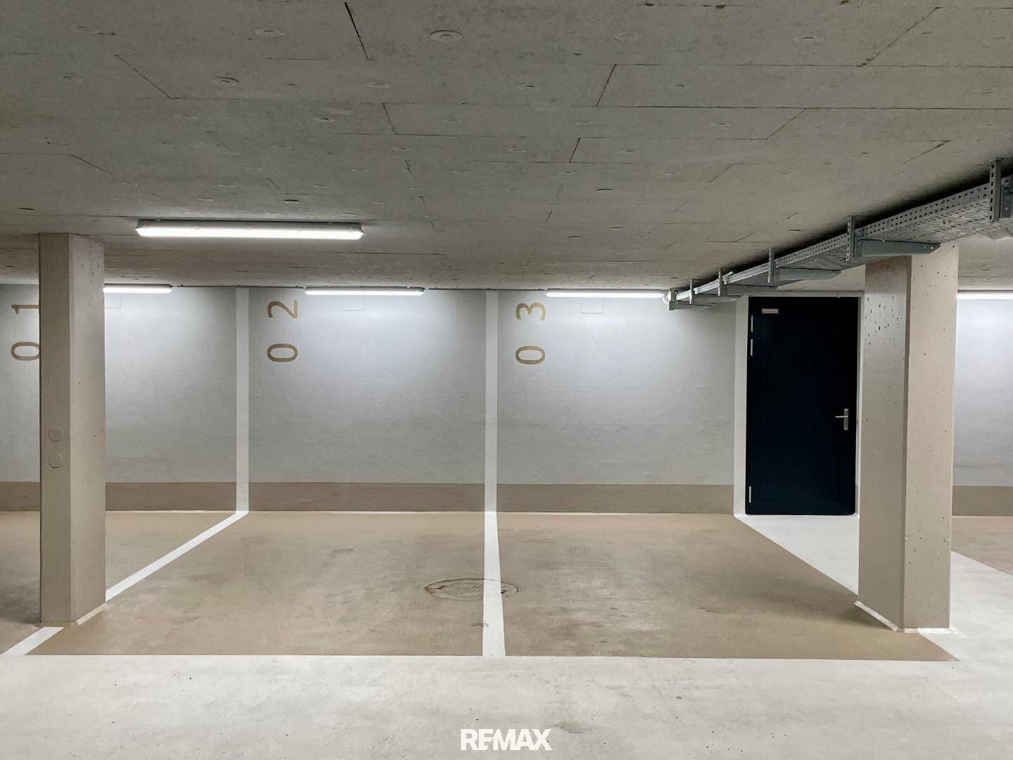Tiefgarage mit mehreren markierten Stellplätzen und Betonwänden, gut beleuchtet für sicheres Parken.