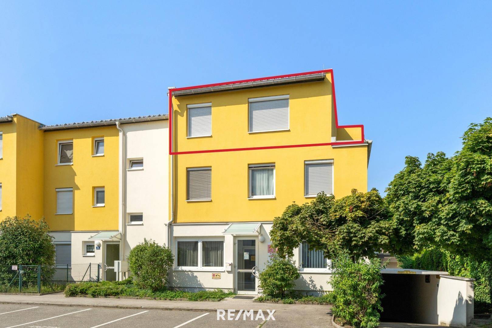 Gelbes Mehrfamilienhaus mit roten Umrandungen, das die zum Verkauf stehende Einheit hervorhebt.