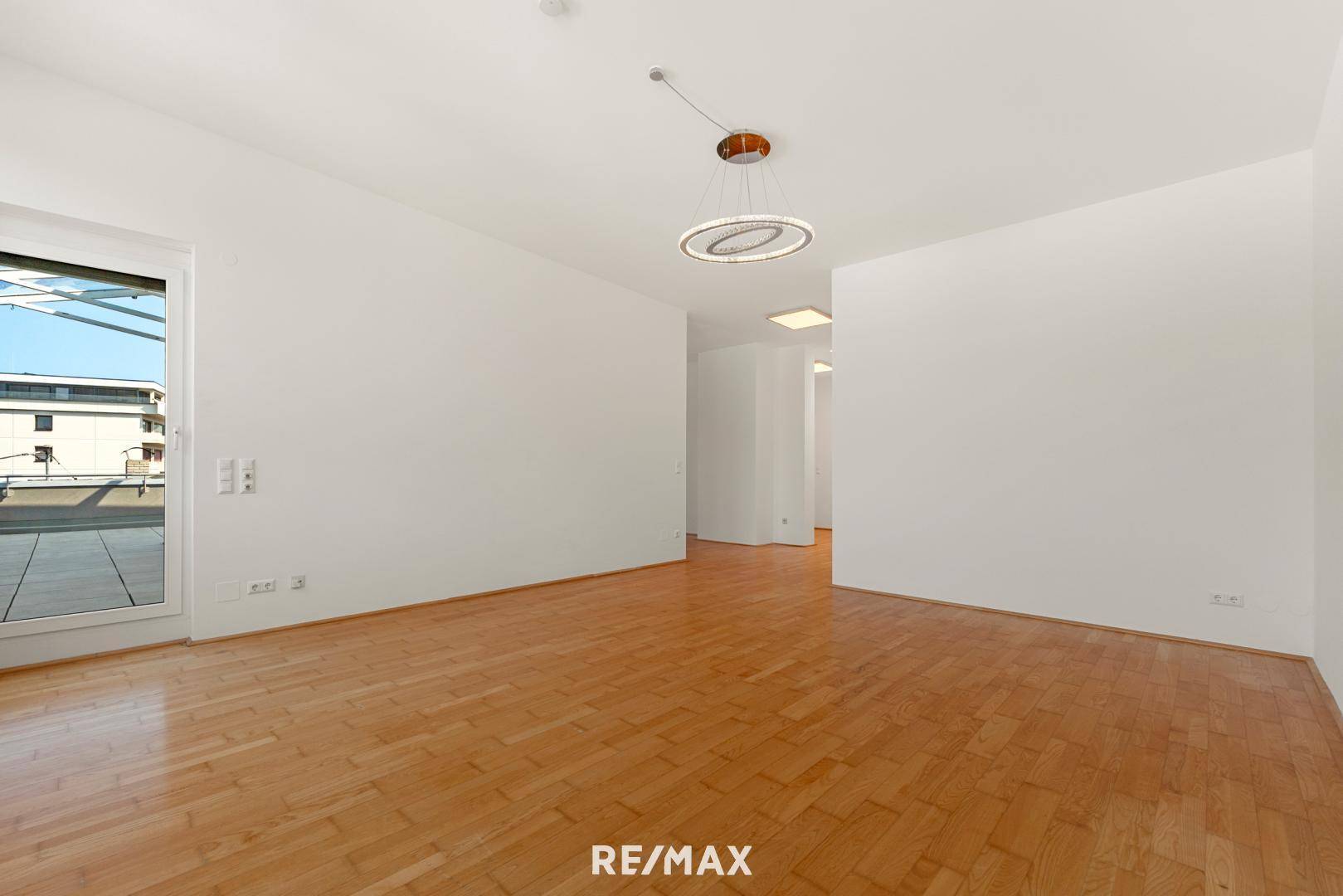 Heller Wohnbereich mit Parkettboden und direktem Zugang zur großen Außenterrasse.