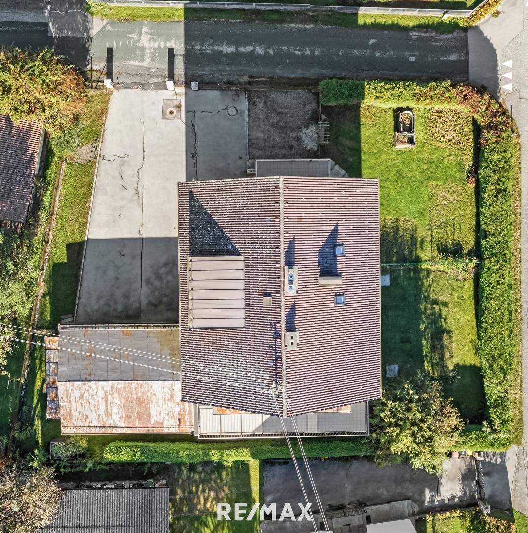 Luftaufnahme eines Wohnhauses mit Satteldach, umgeben von Grünflächen und einer Zufahrt.