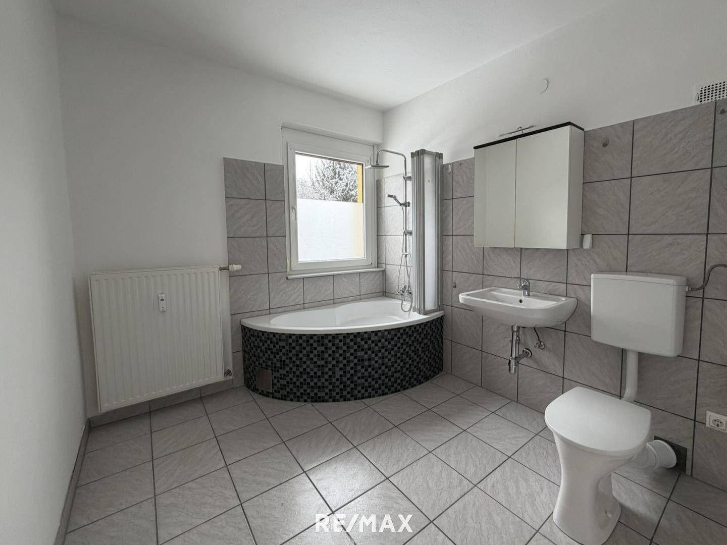 Badezimmer mit Eckbadewanne, Duschfunktion, WC, Waschbecken und Fliesenboden.