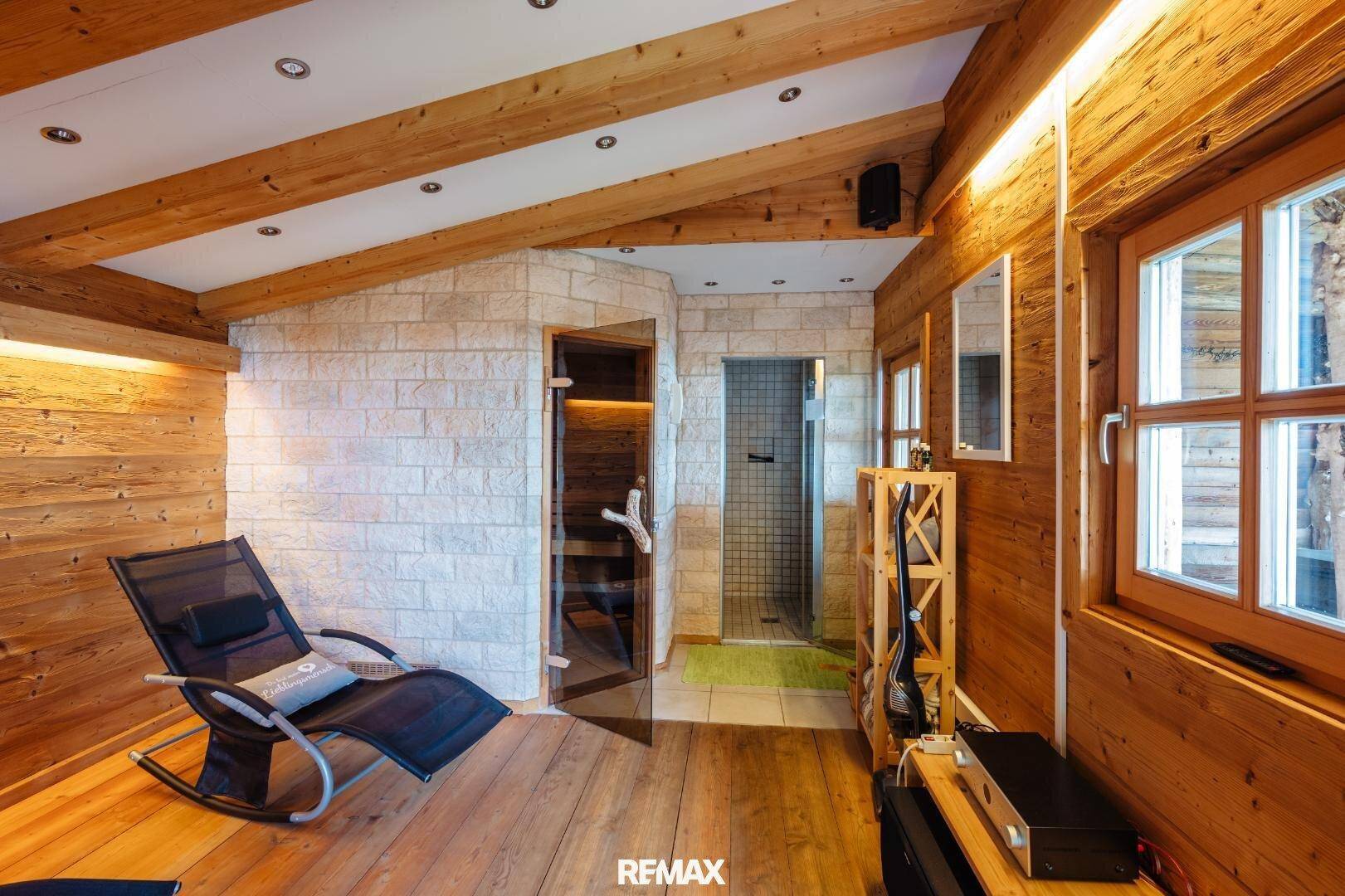 Exklusiver Wellnessbereich mit Sauna, Steinwand, Holzverkleidung und Entspannungsliege.