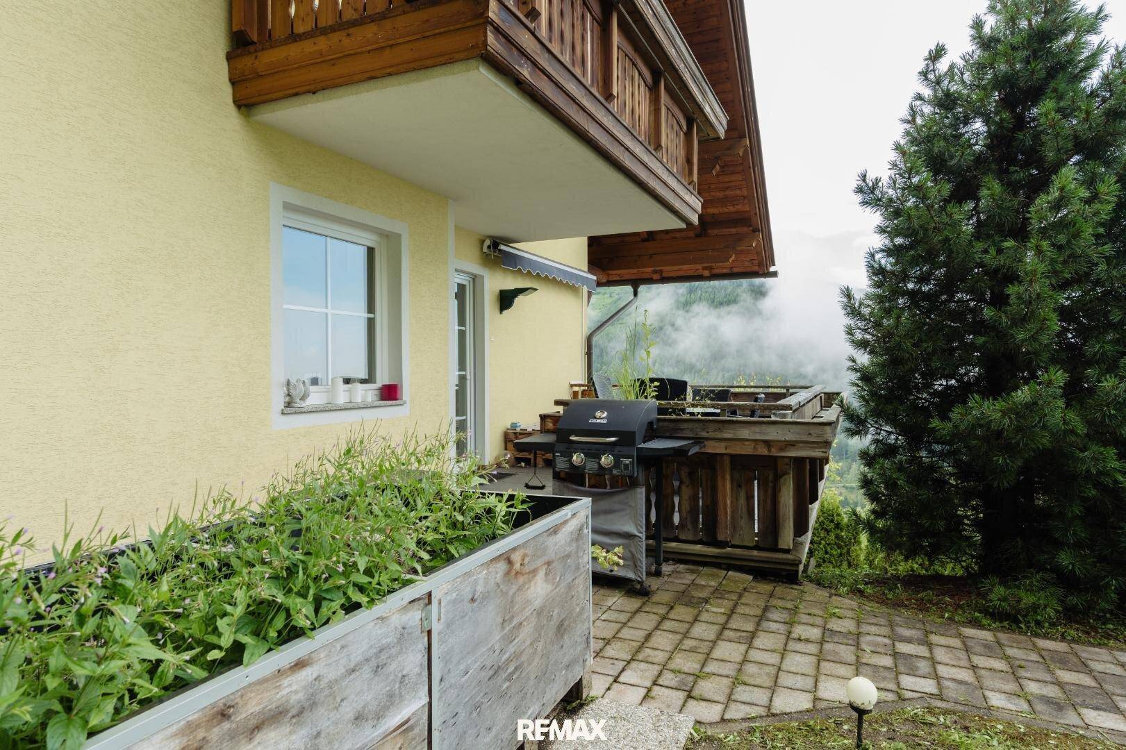 Außenbereich mit Grillplatz, gepflasterter Terrasse und Blick auf die umliegende Berglandschaft.