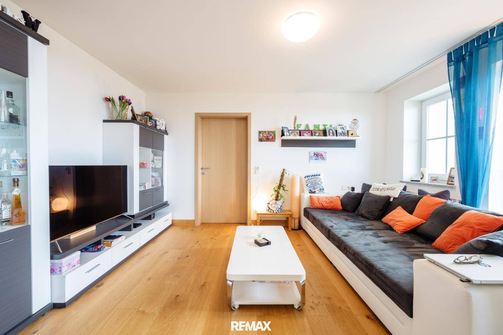 Gemütliches Wohnzimmer mit großem Sofa, Holzboden und modernen Möbeln, ideal zum Entspannen.