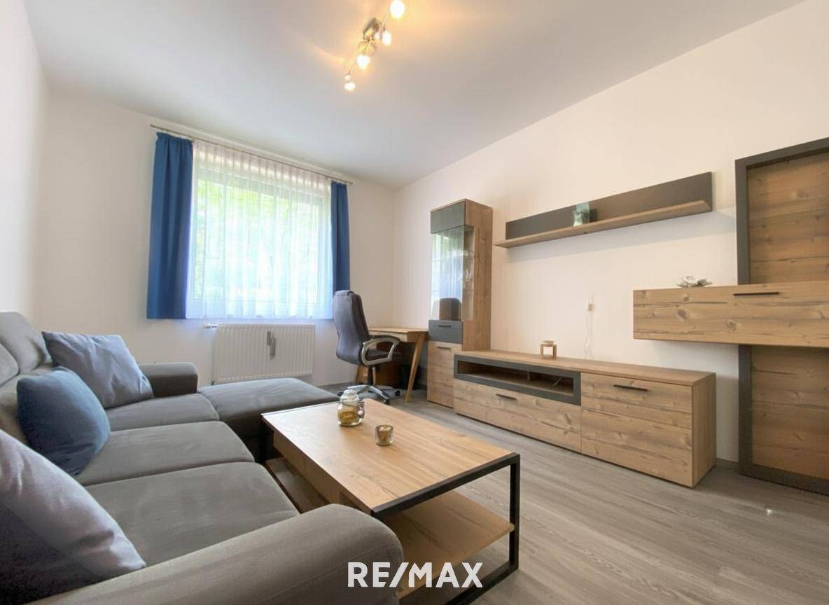 Helles Wohnzimmer mit modernem Sofa, Couchtisch und großer Medienwand aus Holz.