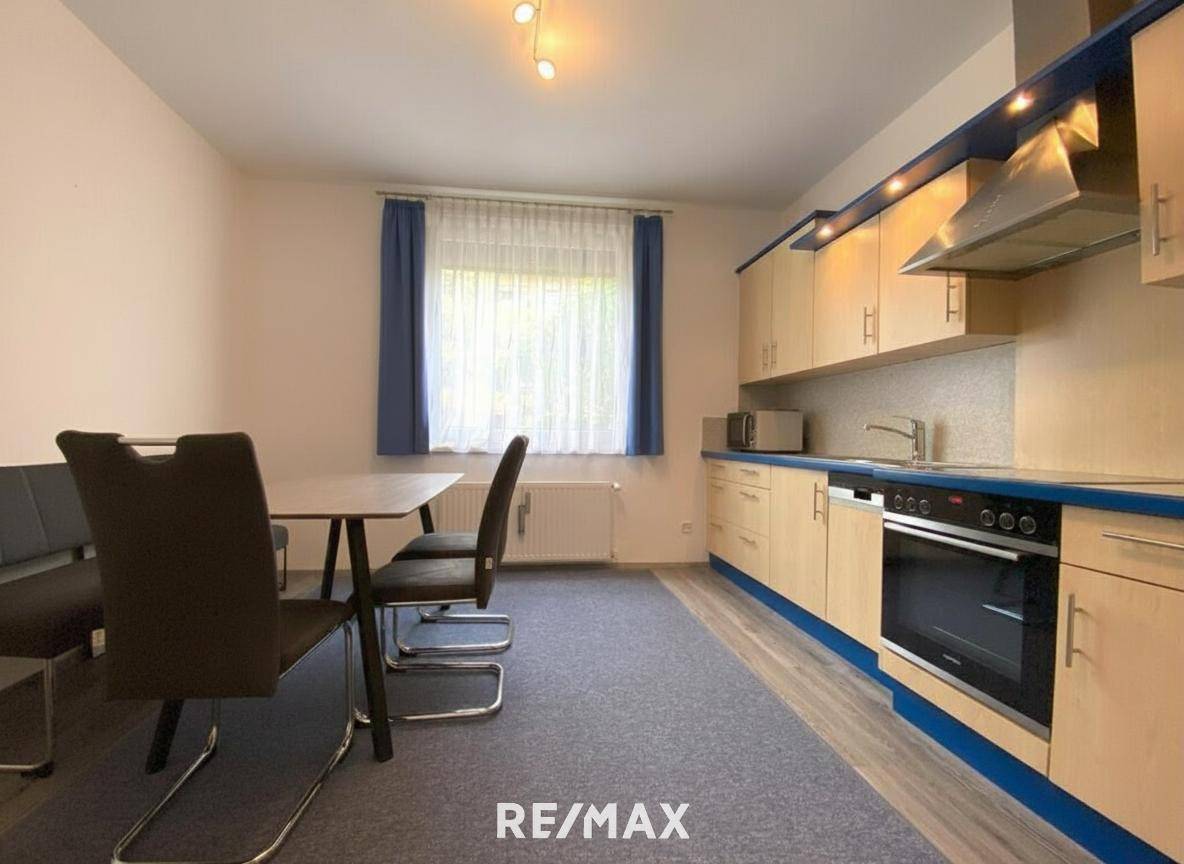 Funktionale Einbauküche mit hellen Holzfronten, blauen Akzenten und Essbereich.