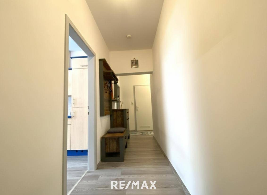 Langer Flur mit Laminatboden und Garderobe, der zu weiteren Räumen führt.