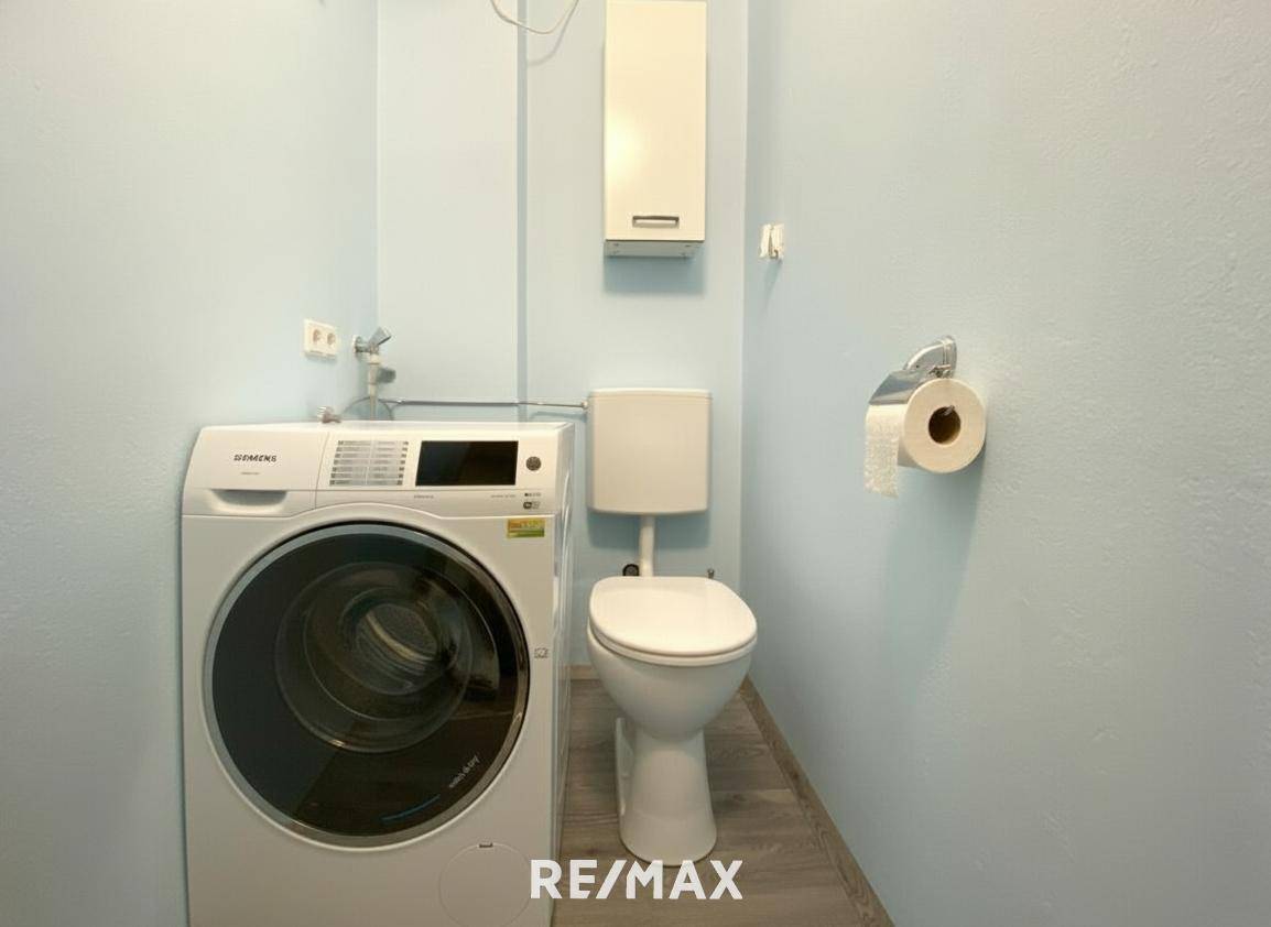 Separate Toilette mit Waschmaschine und hellblauen Wänden.