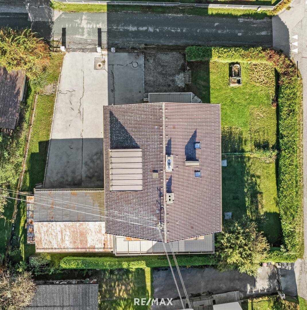 Luftaufnahme des Gebäudes mit Satteldach, umgebender Grünfläche und Straße.