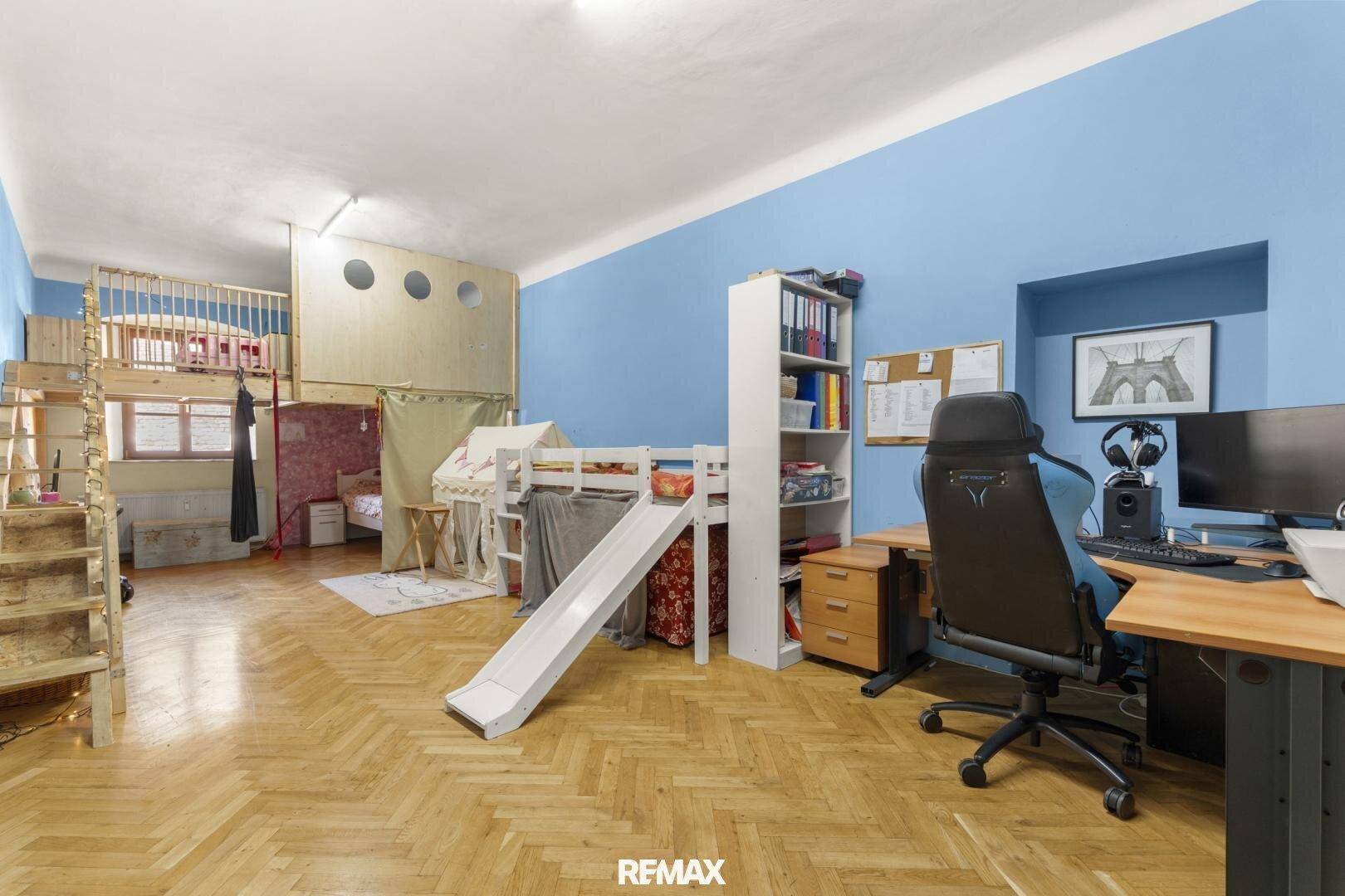 Kinderzimmer mit Holzboden, blauen Wänden und einem Hochbett mit Rutsche.