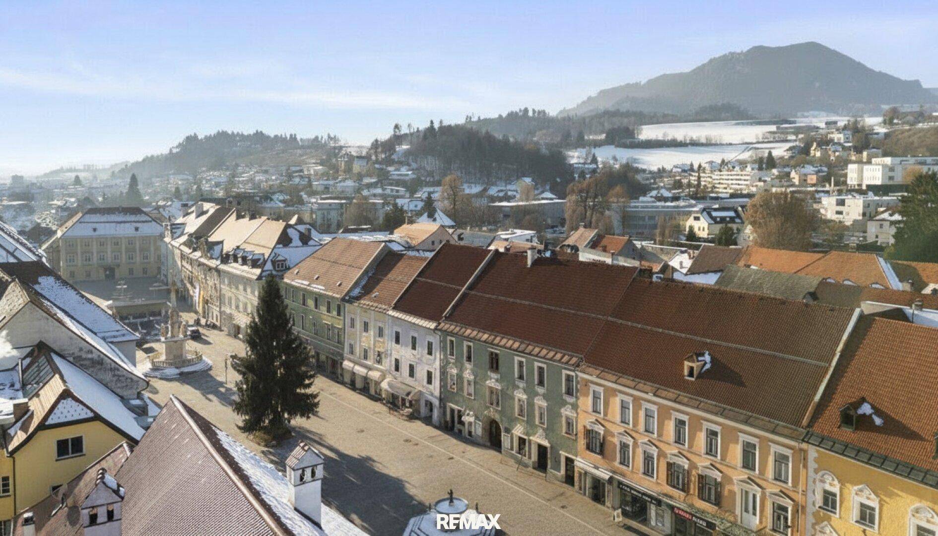 Weitläufiger Blick über die Stadt mit traditionellen Gebäuden und schneebedeckten Hügeln.