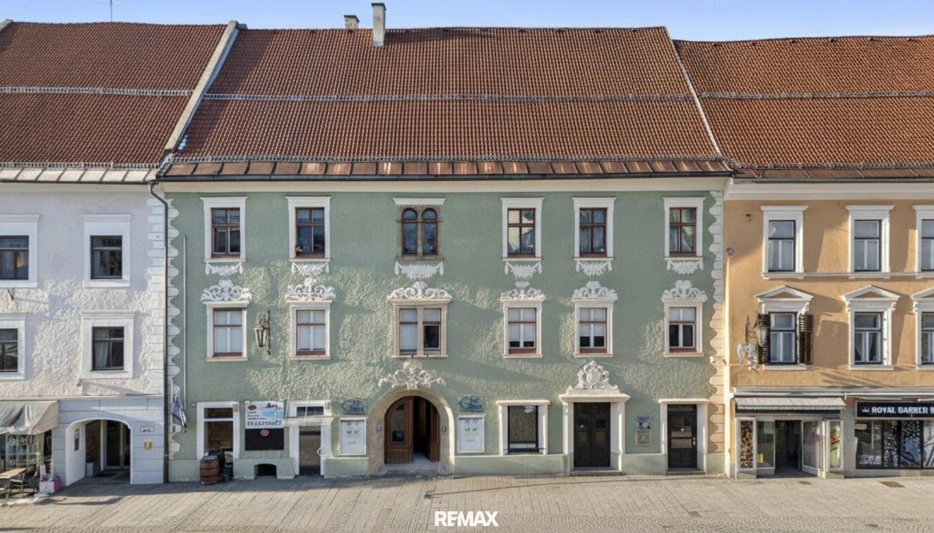 Detailansicht einer historischen Fassade mit dekorativen Elementen und mehreren Fenstern.