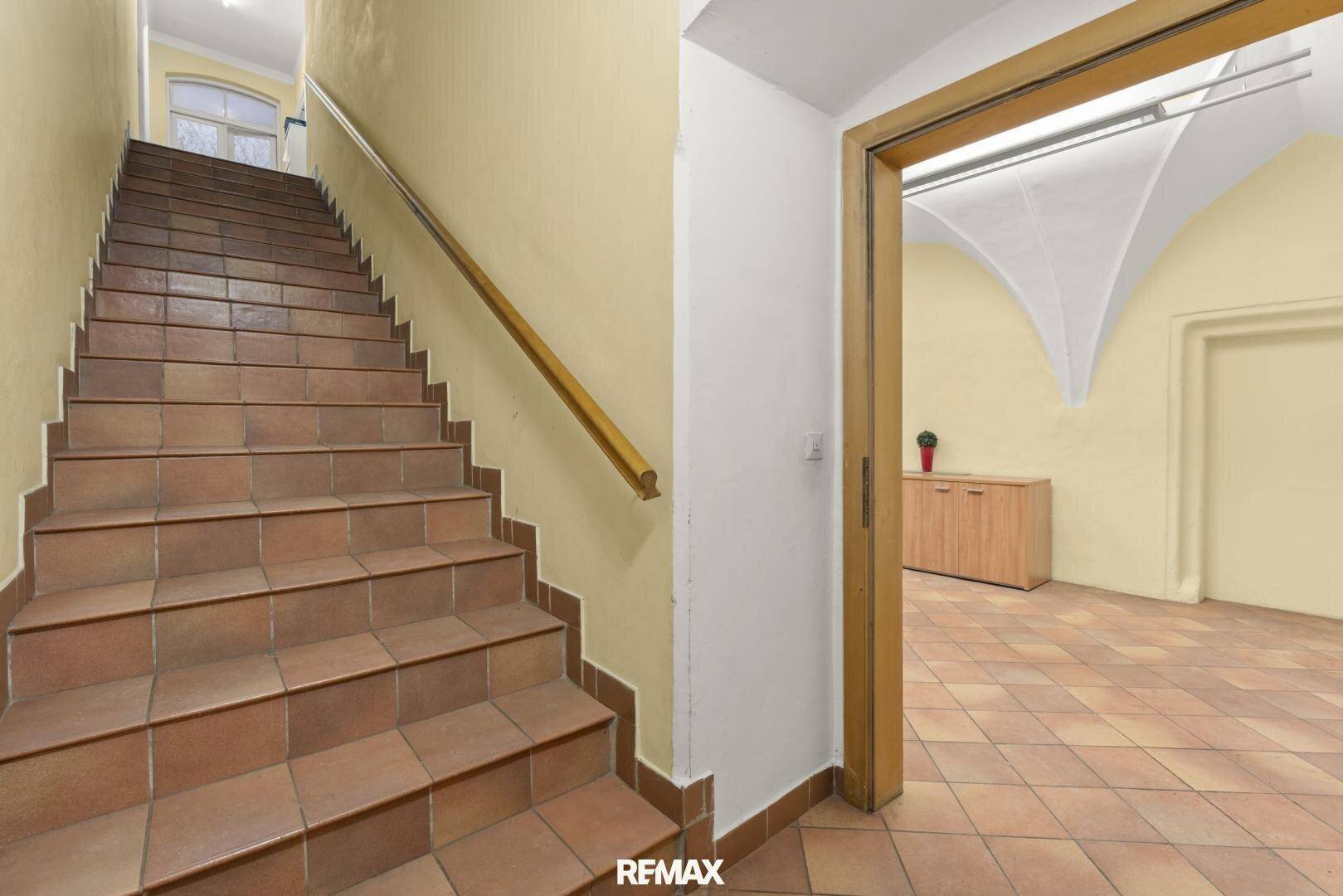 Geflieste Treppe mit Holzgeländer, die zu den oberen Etagen führt.