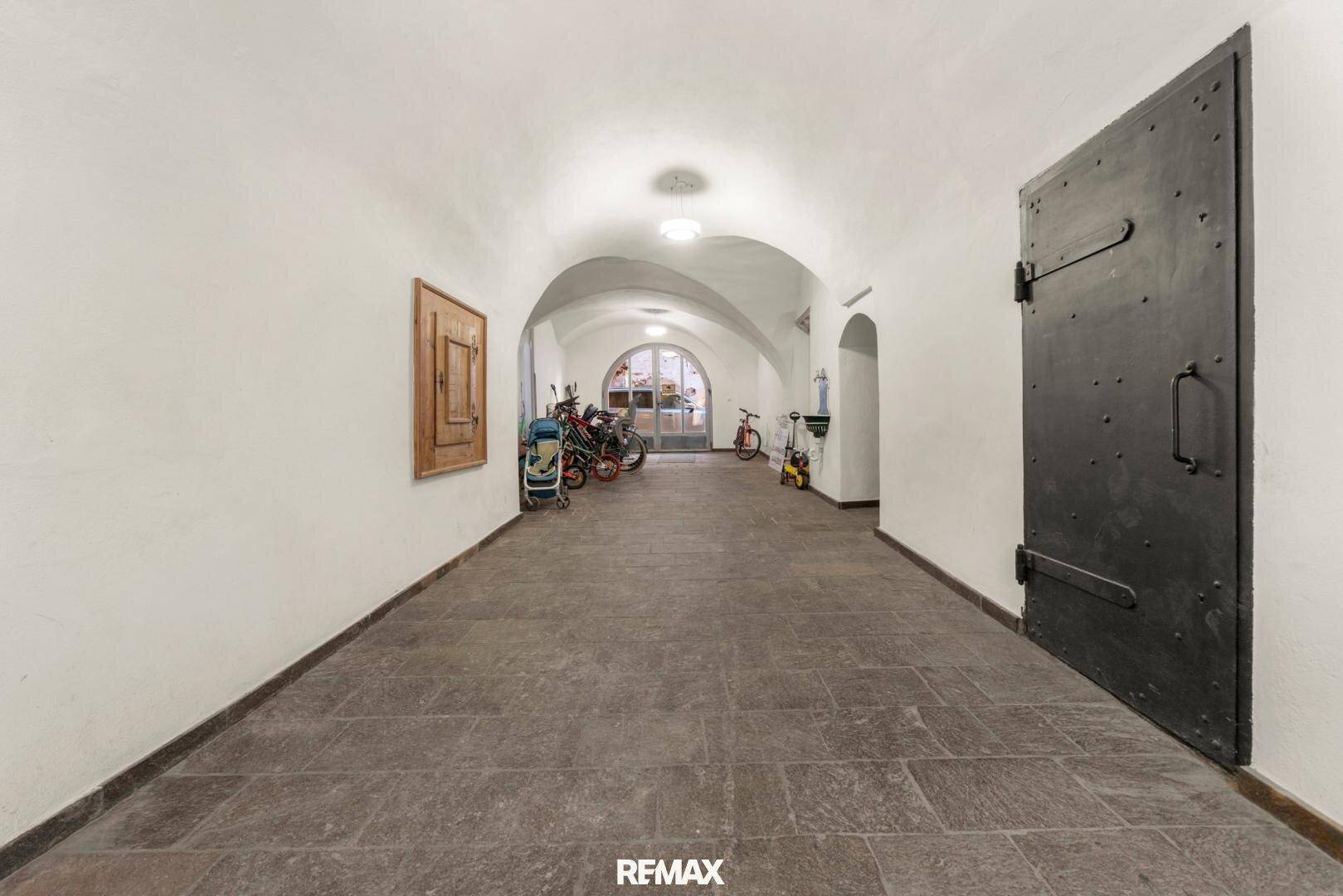 Historischer Gang mit Steinboden und gewölbter Decke, der als Fahrradabstellplatz genutzt wird.